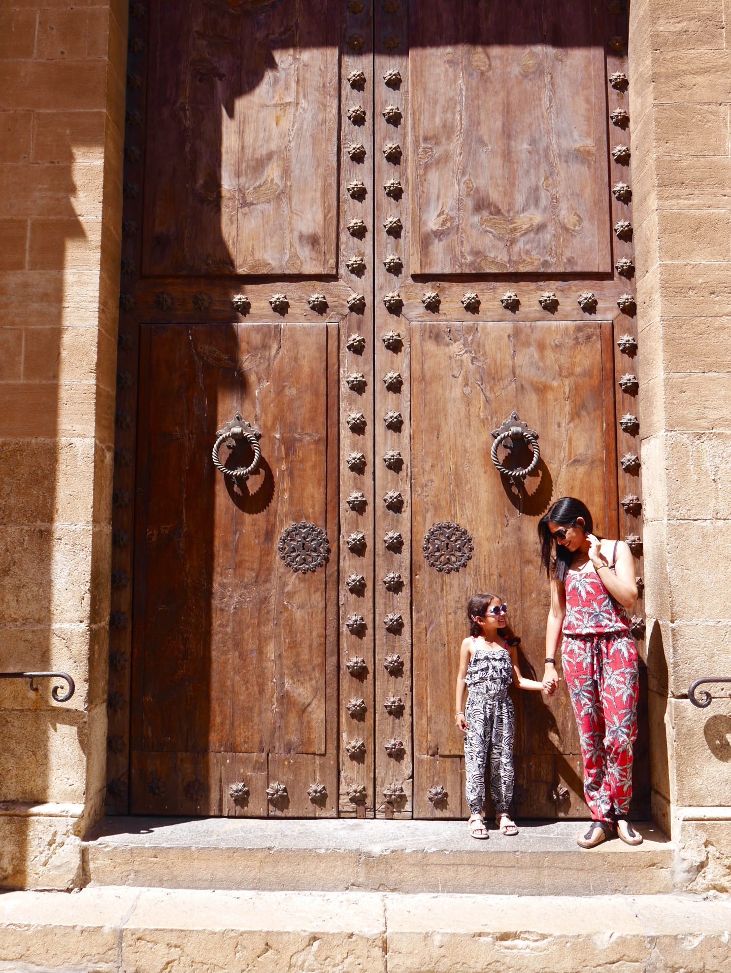 Picture of sima and daughter both in sunglasses in front of a big door in Placa Mayor Mallorca