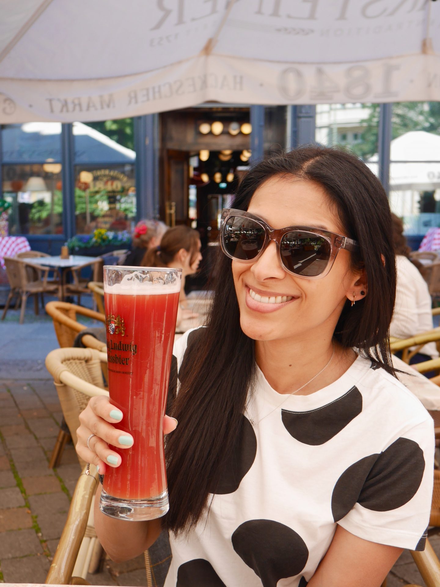Sima in black and white polka dot t-shirt and a large glass of red Berlin beer