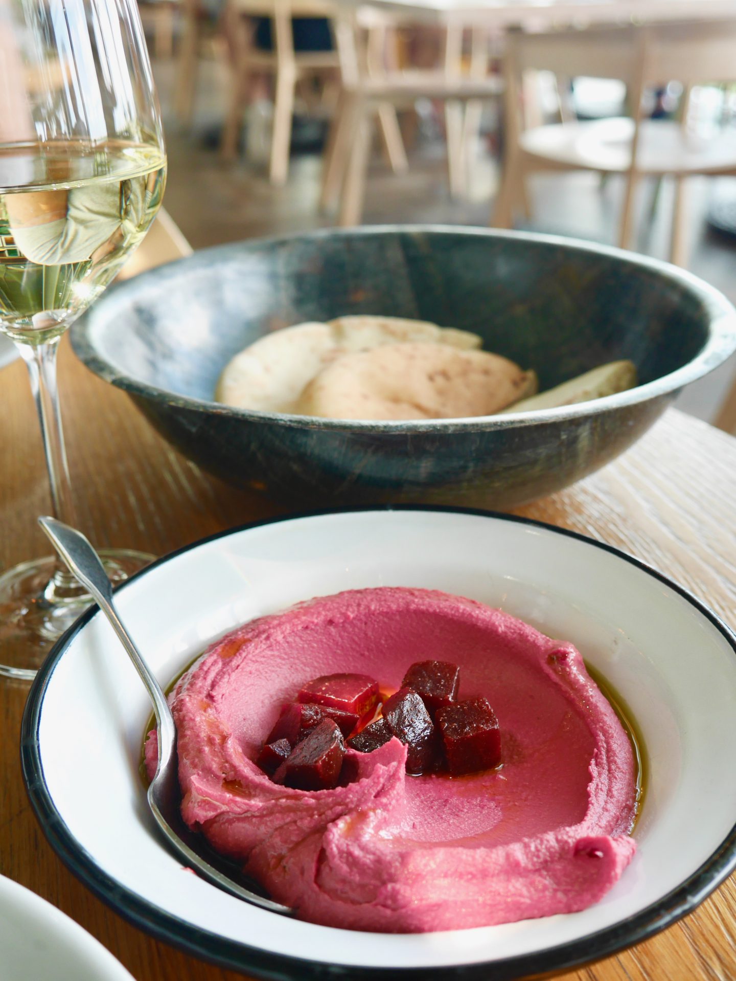 beetroot and horseradish hummus in a white bowl served with warm pita bread.