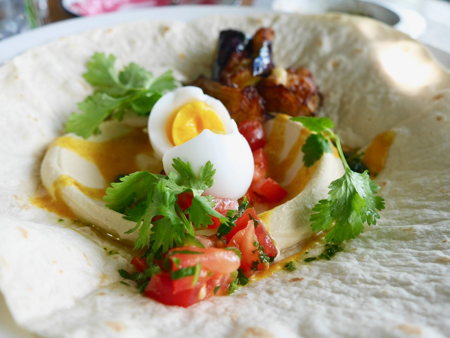 baked eggplant, hummus, tomato salsa, tahini with amba and soft boiled egg served on a laffa bread.