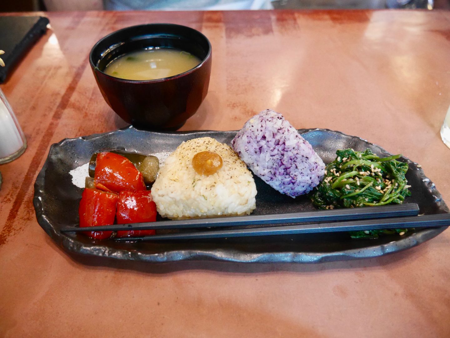 two onigiri rice balls seasoned with purple shiso, served with vegetable side dishes and vegan miso soup