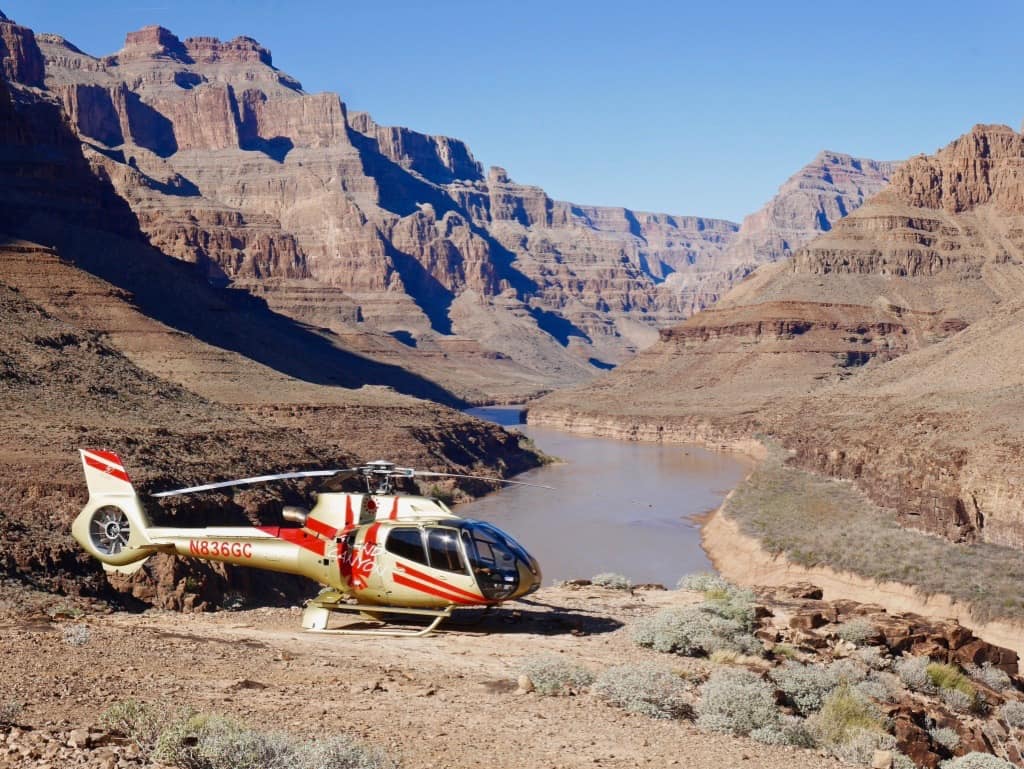 view of a gold and red helicopter parked within the Grand Canyon