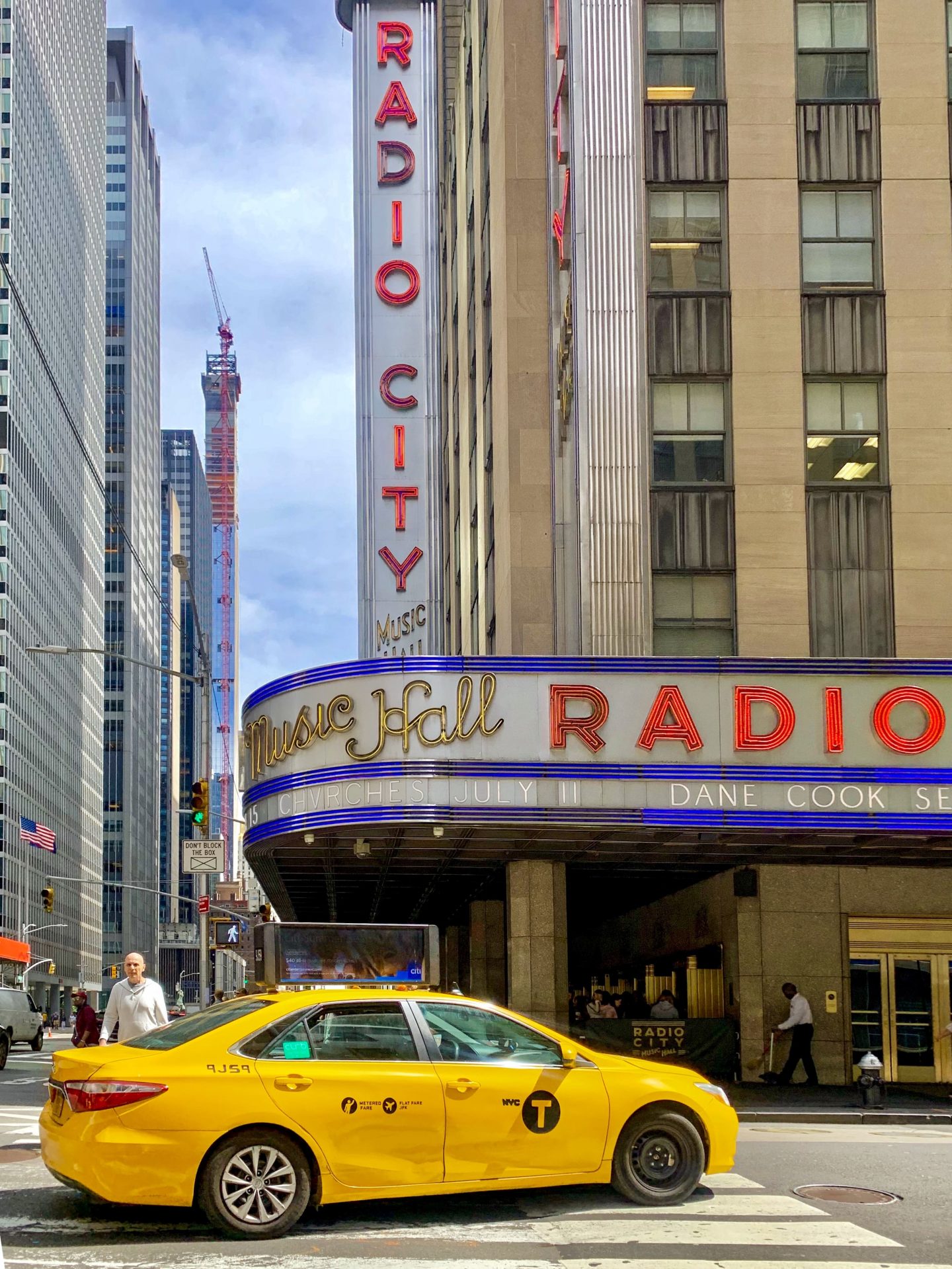photo of out side of Radio City music hall with yellow NYC taxi
