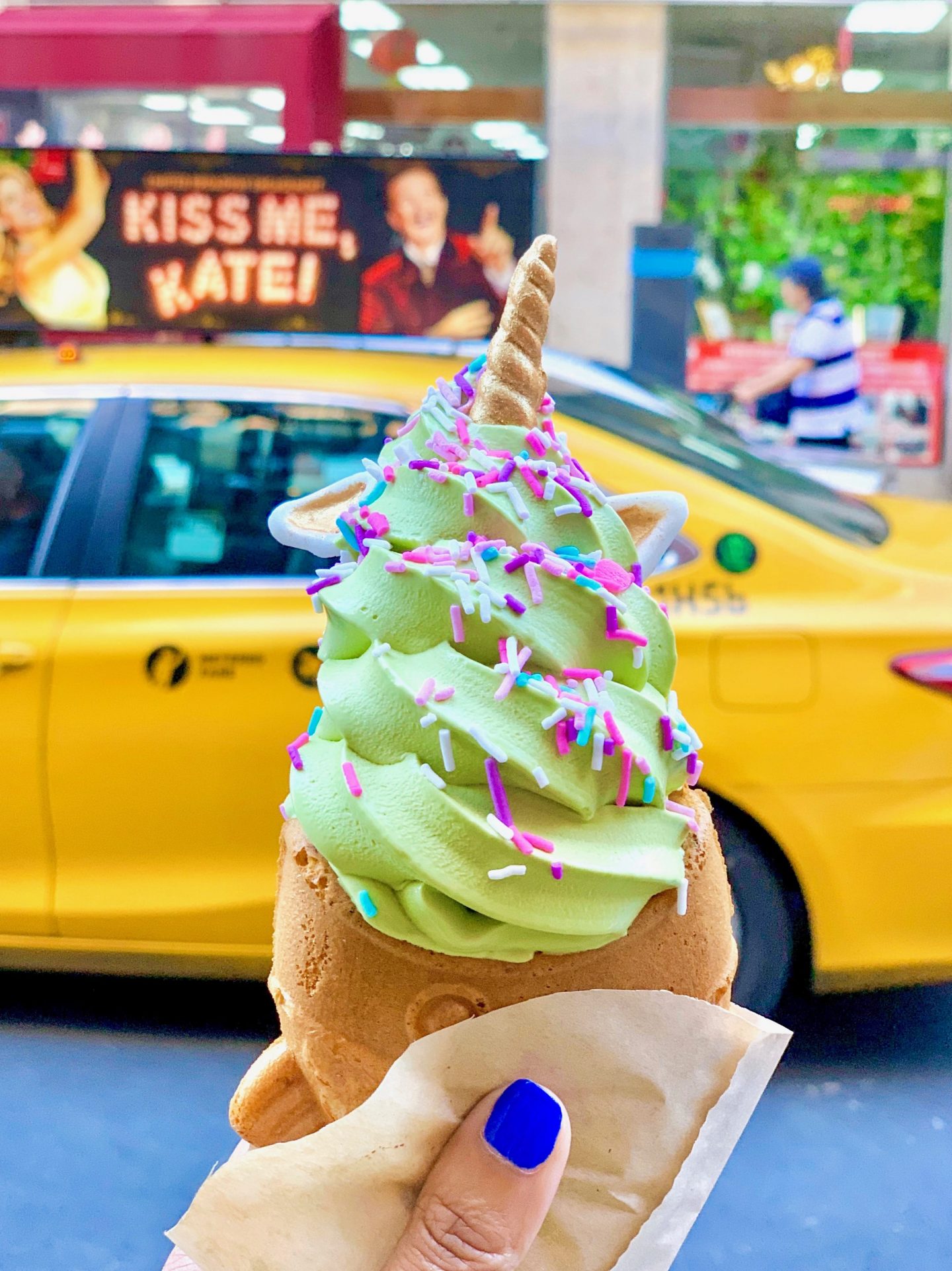 Japanese fish-shaped cake with green soft serve ice cream and sprinkles in front of yellow NYC taxi