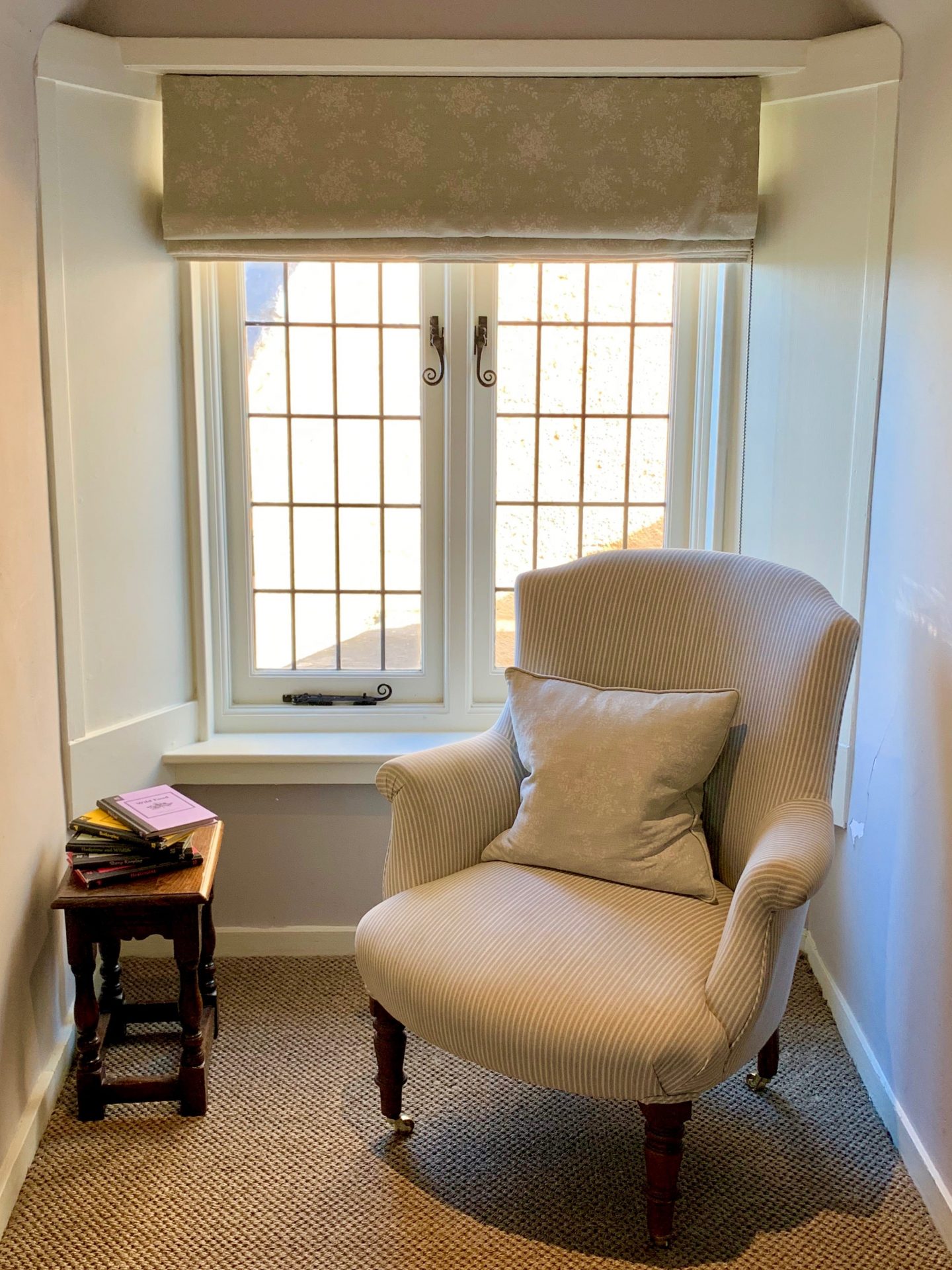 chair in front of sash window alongside table with 5 books
