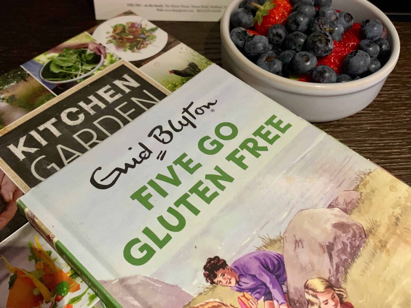 book from reading corner 'enid Blyton' along side blue berries and strawberries in a bowl