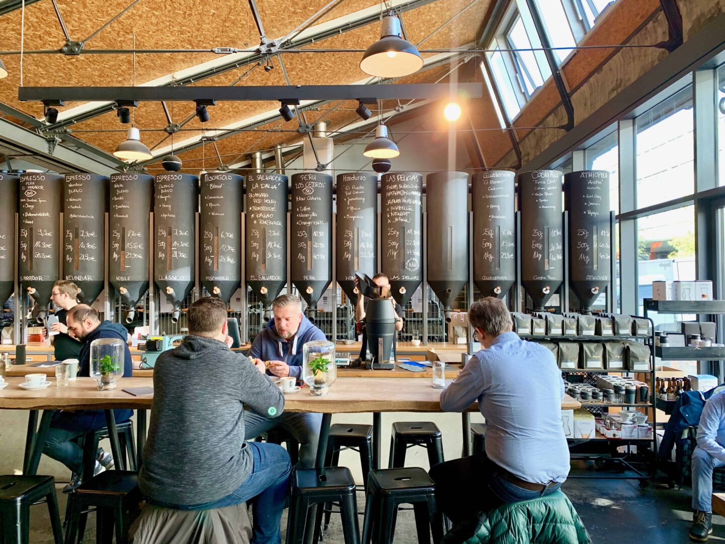 view looking towards the coffee bean storage, black stools and oak tables