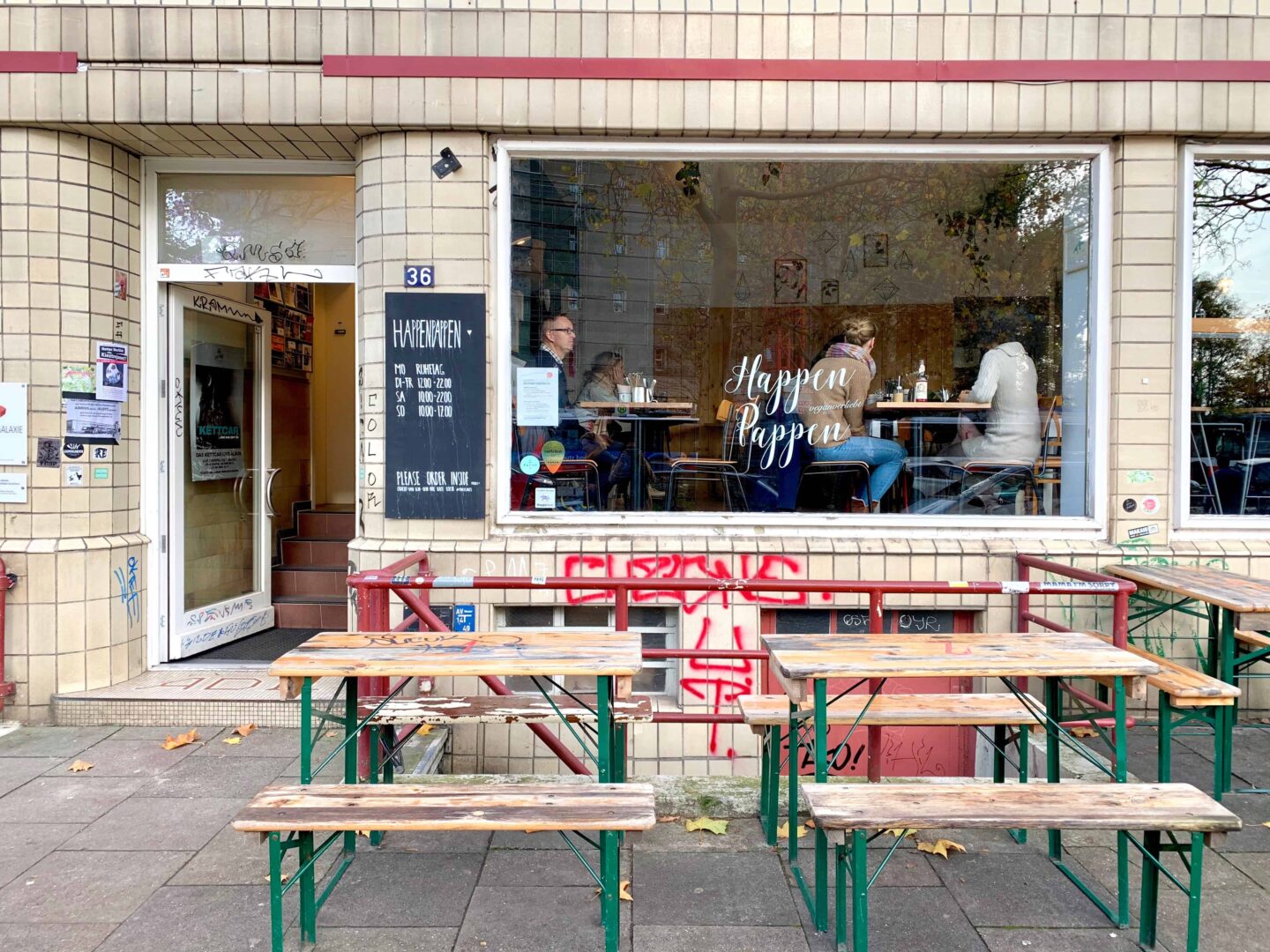 outside of the Happenpappen with benches outside and red graffiti on the staircase leading downstairs