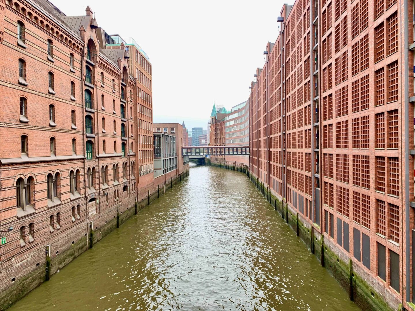 looking down the Speicherstadt water front surrounded by red brick warehouse on either side