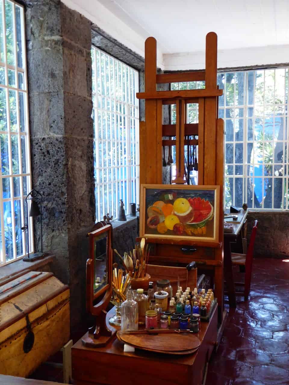 view of an artist set up including paints and an easel in the former home of Frida Kahlo