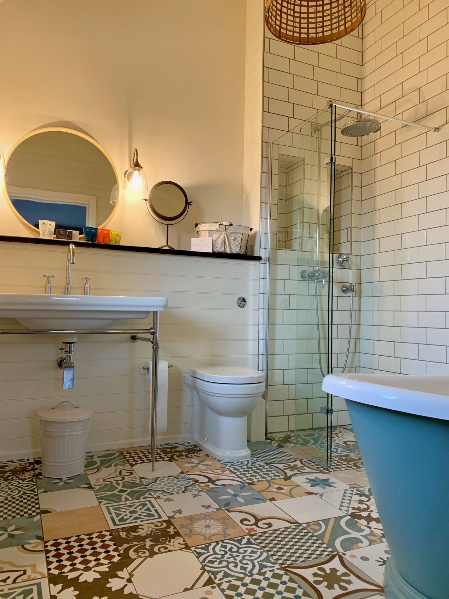 bathroom in the fish hotel in the cotswolds with white tiles, freestanding bath and pattered floor