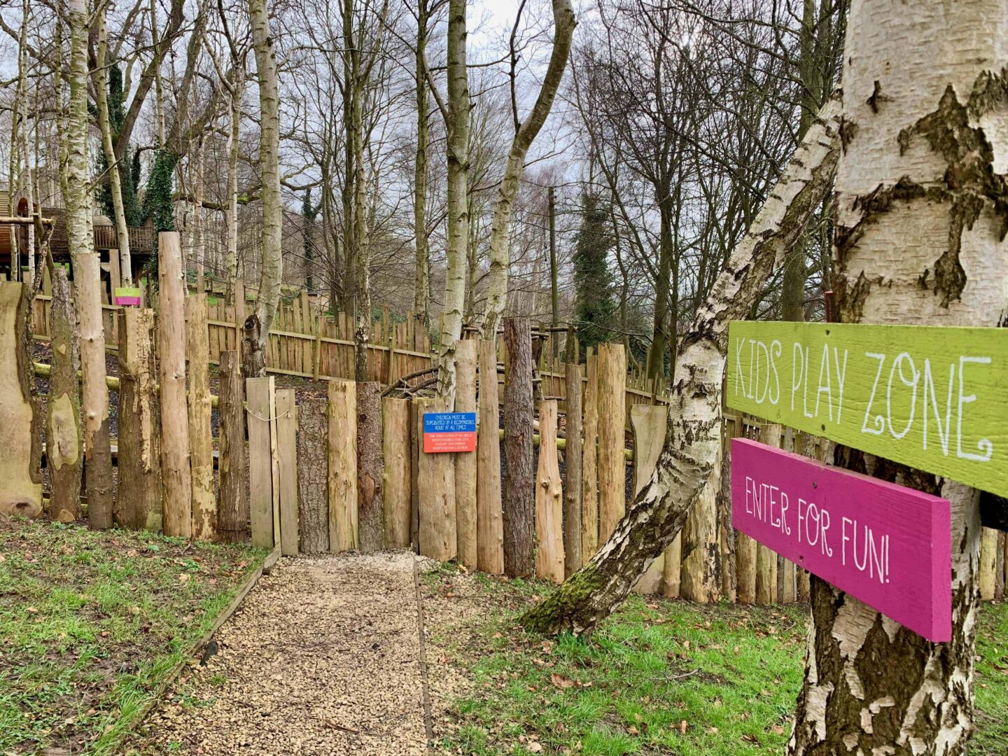 view looking towards to the kids play zone pink and green sign stuck on a tree