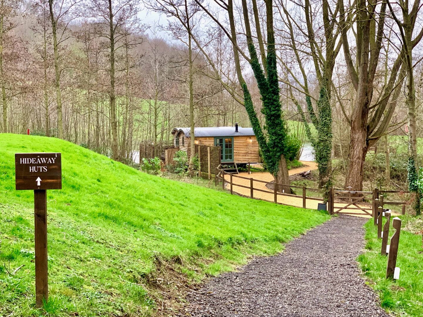 image of a gravel path with a sign pointing towards the 'hideaway huts' in The Fish Hotel Cotswolds