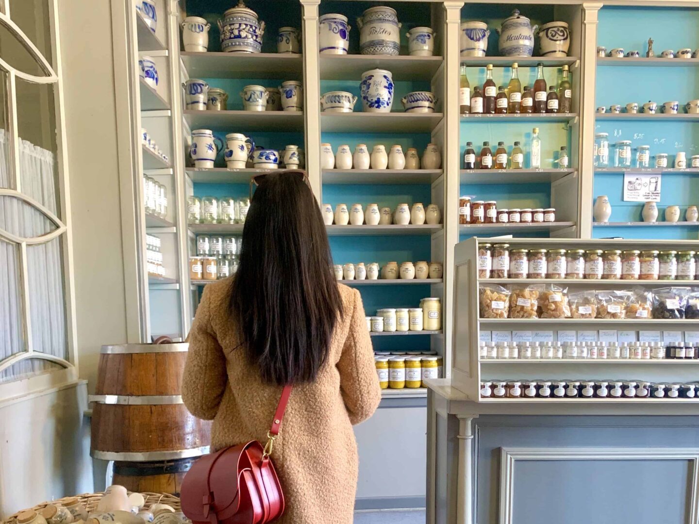 sima looking towards the foods on a shelf in a shop holding a red bag