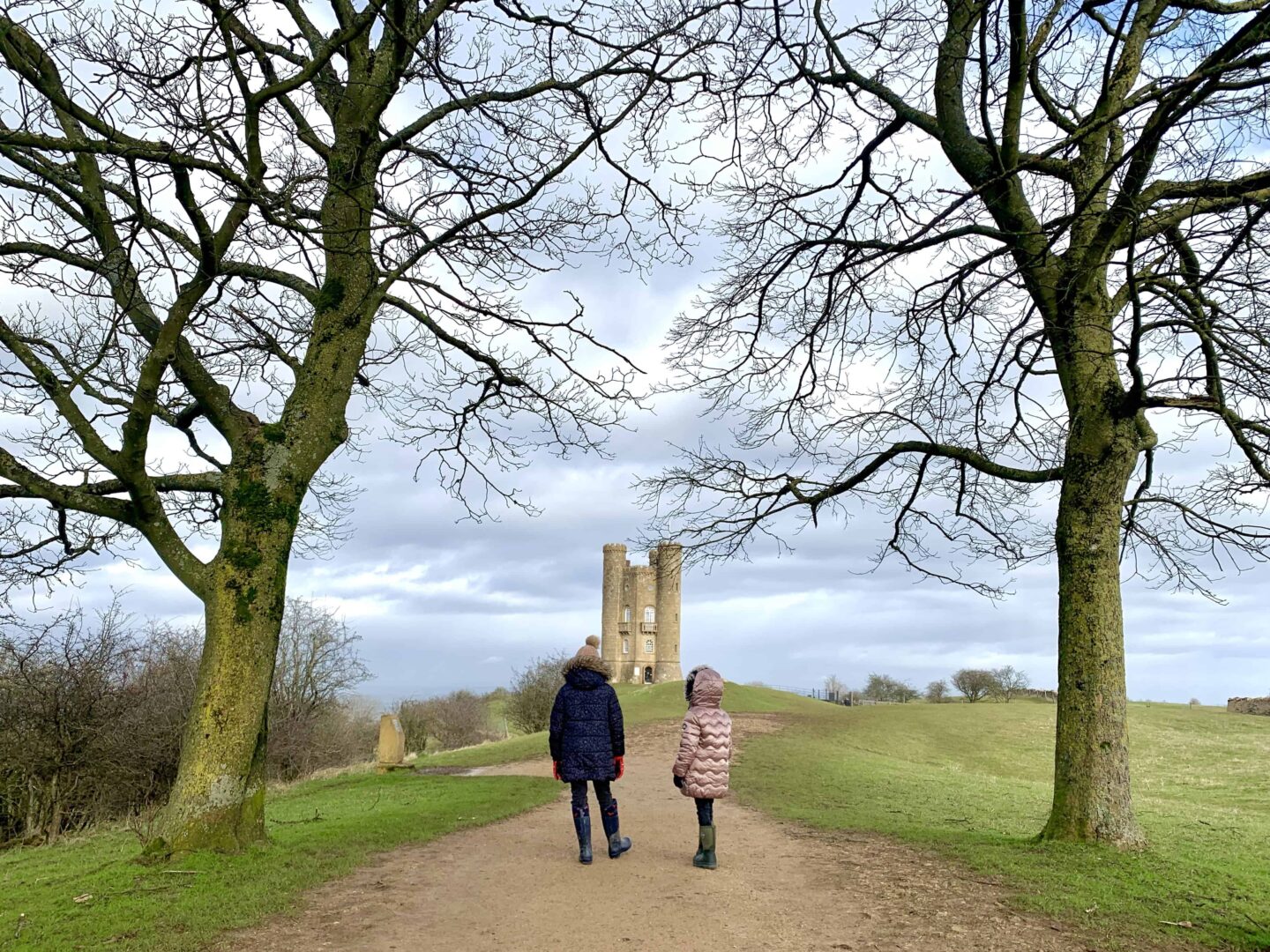 two children looking towards an old castle on top of a hill
