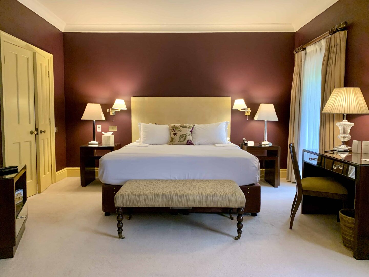 bedroom with stool at the bottom of the bed and red walls