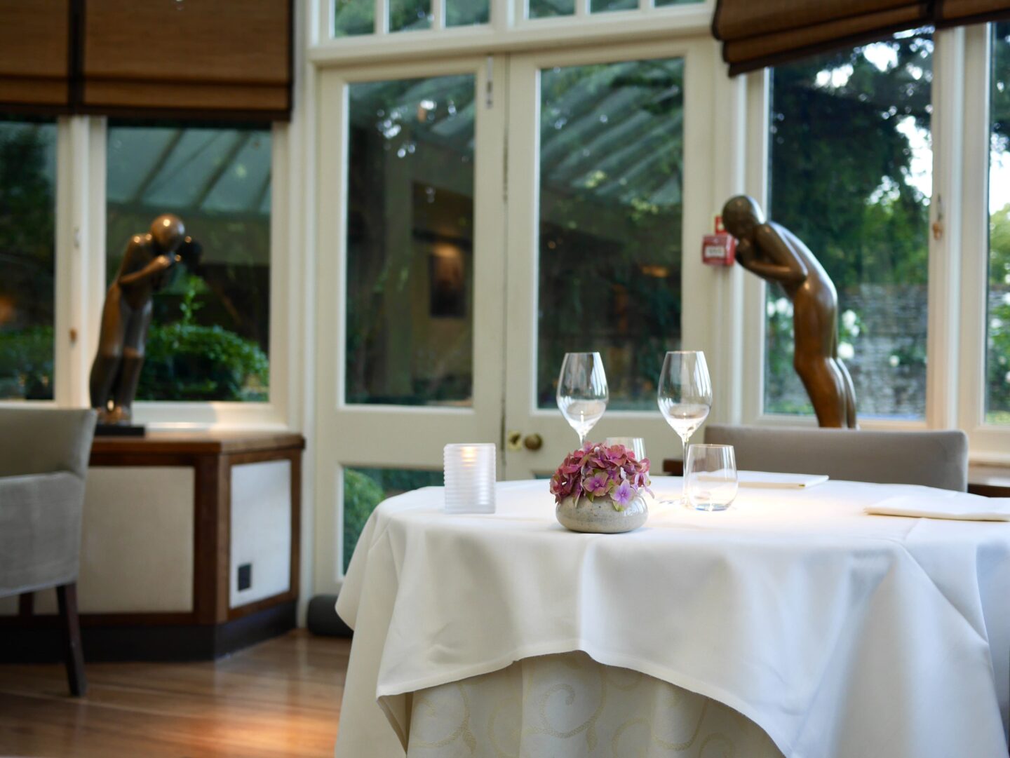 view of the table with white table cloth, flowers, ornaments in the ceiling height windows