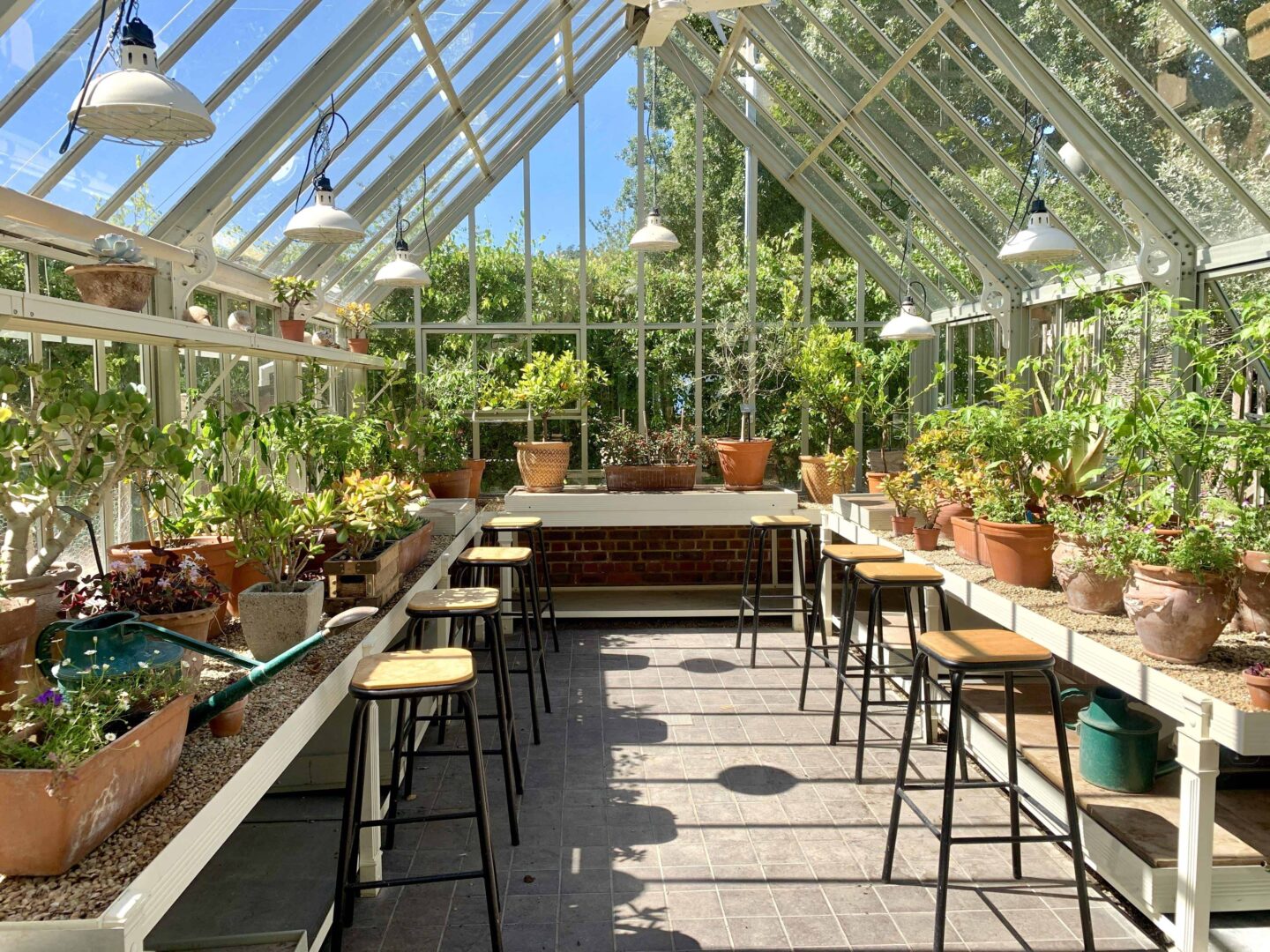 inside of a greenhouse with pots, plants and stools