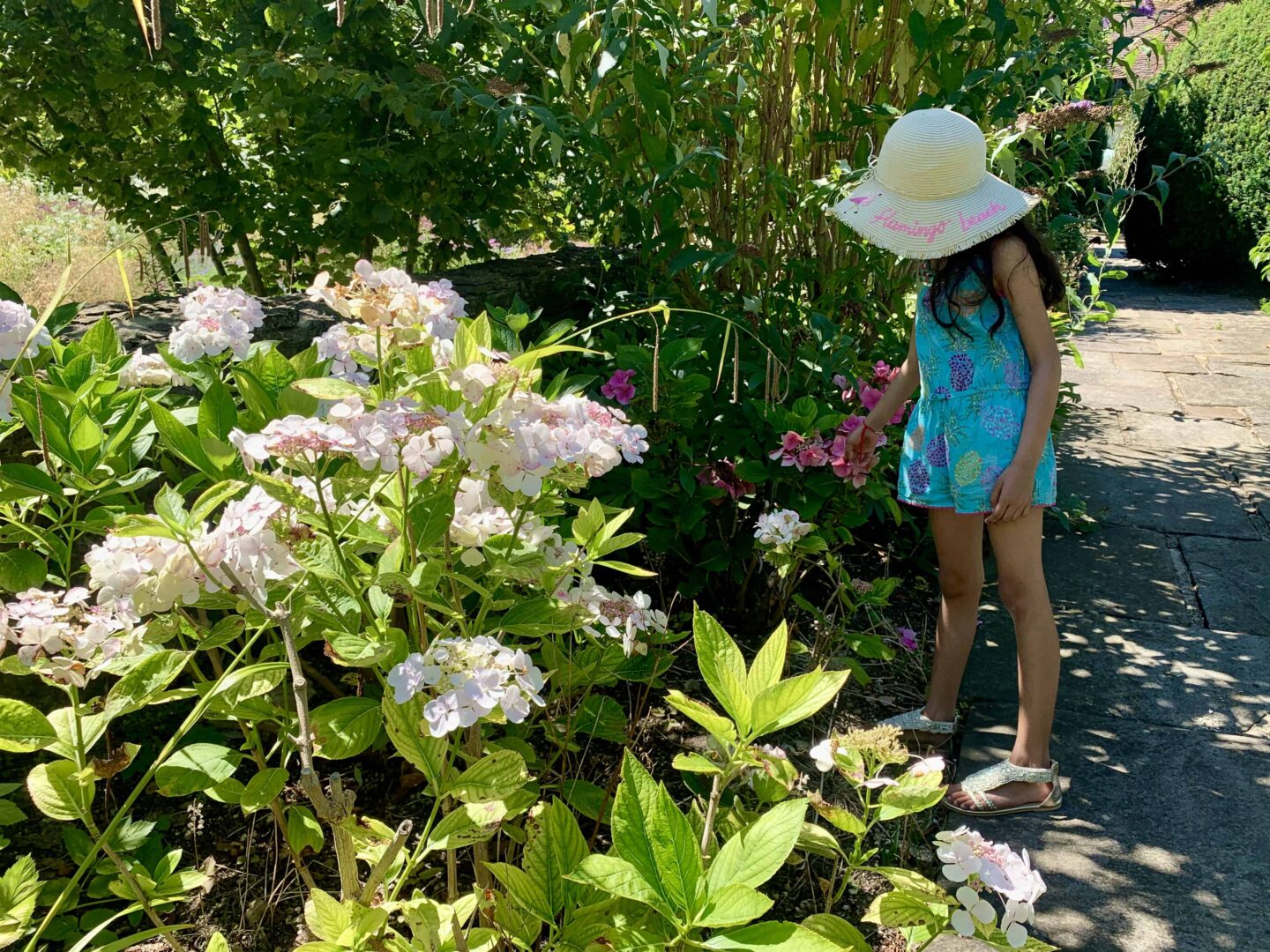 simas daughter in a straw hat looking at the flowers in the garden