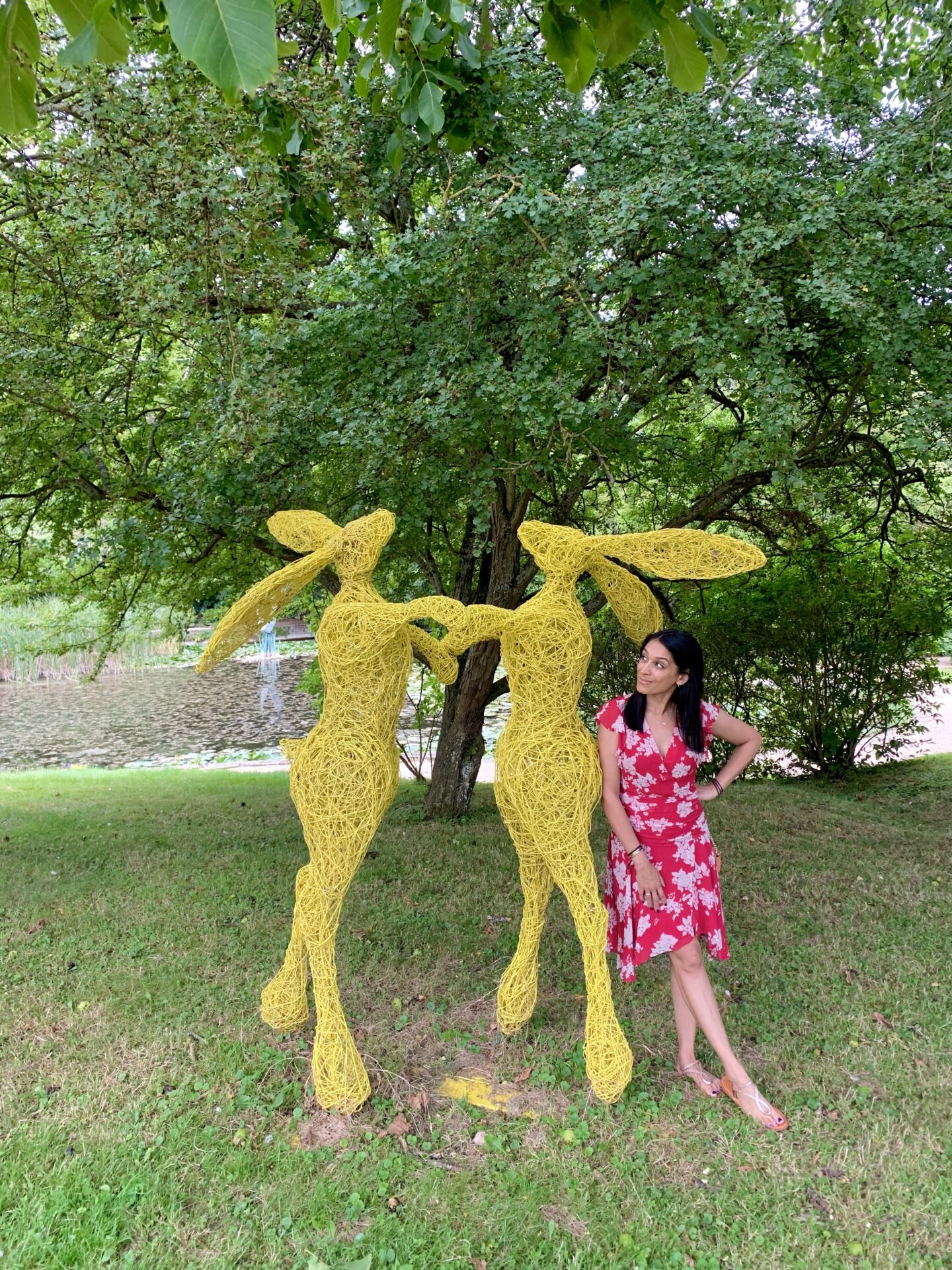 sima in a red dress stood against the yellow metal bunnies