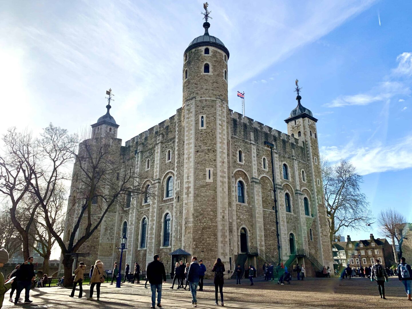view looking upto the Tower of London with people admiring and UK flat on the top