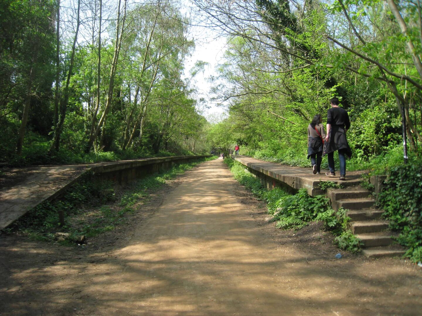 view of an old railway lines with people walking on what would've been the platform.